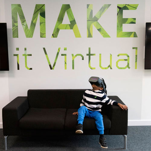 Boy with headset looking at make it virtual sign
